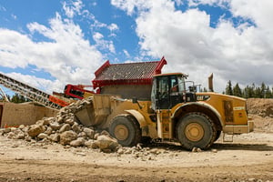 A loader hauls away rock and lost paydirt next to a hopper.